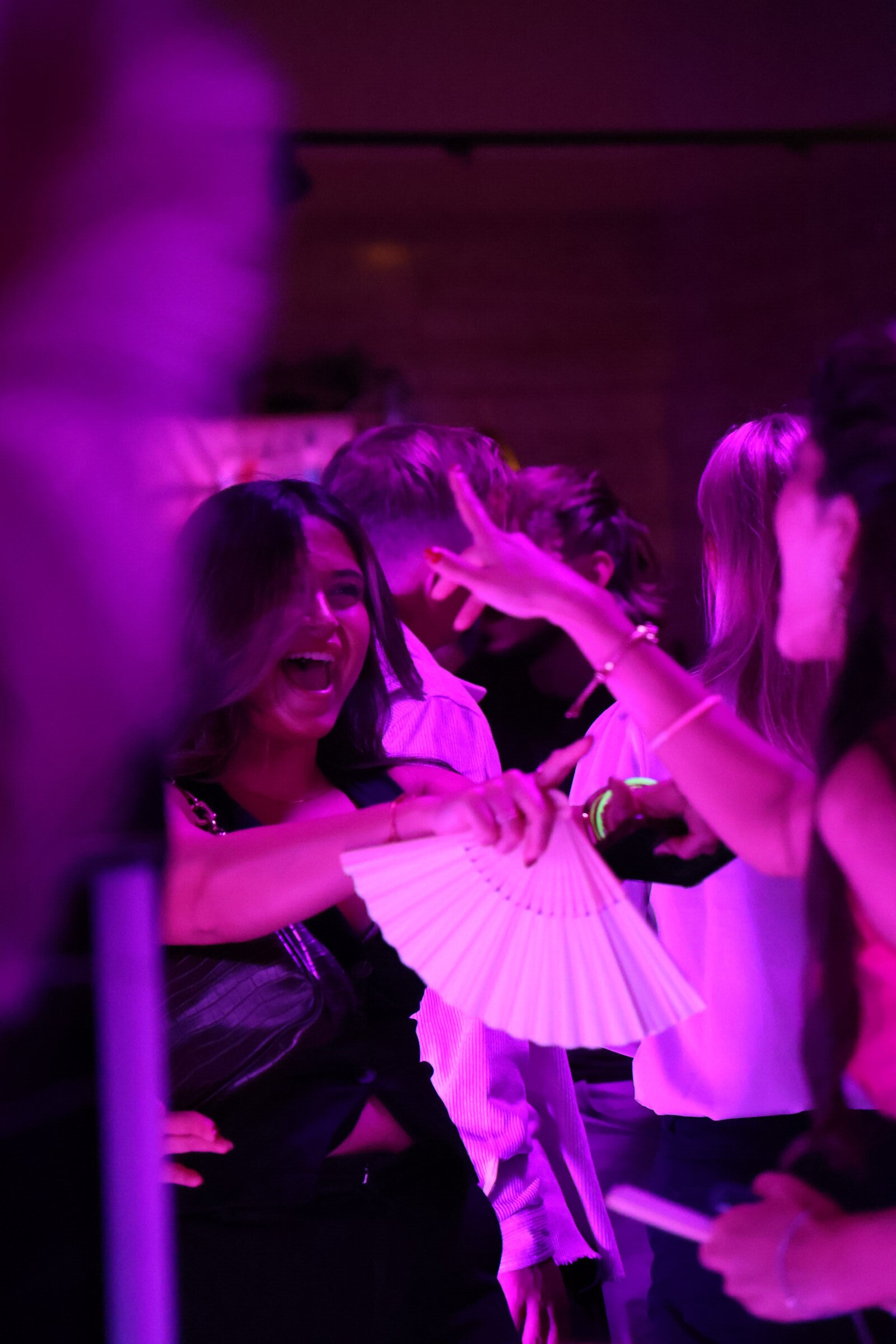 Gäst sjunger med och viftar med fläkt i rosa clubbljus på Nostalgibaren